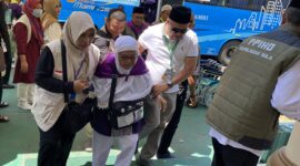 Kabag Kesrah Iksan Dagasuly, kaos Putih (Kiri) saat menunda salah satu CJH Lansia, || Foto: Elang. 